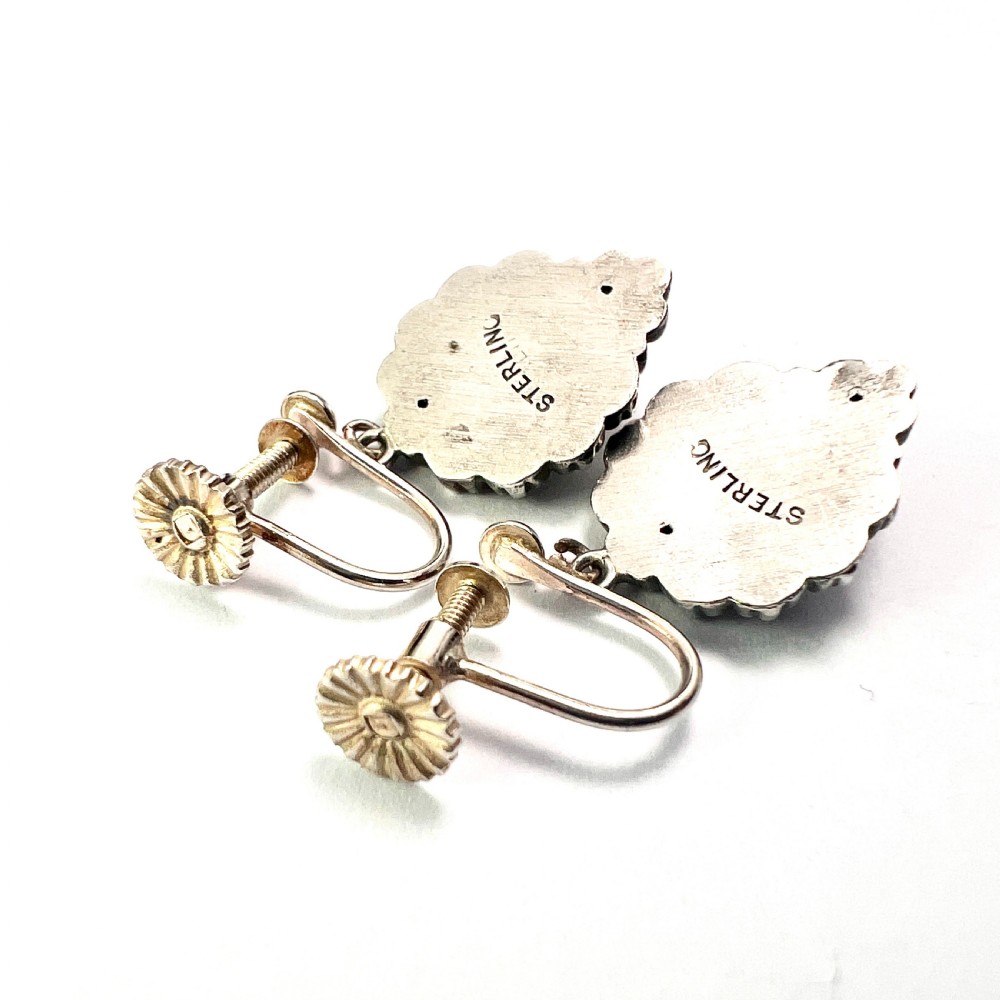 A pair of silver Victorian Aesthetic Era drop earrings featuring a sunburst motif with beaded detailing and screwback fastenings. View V