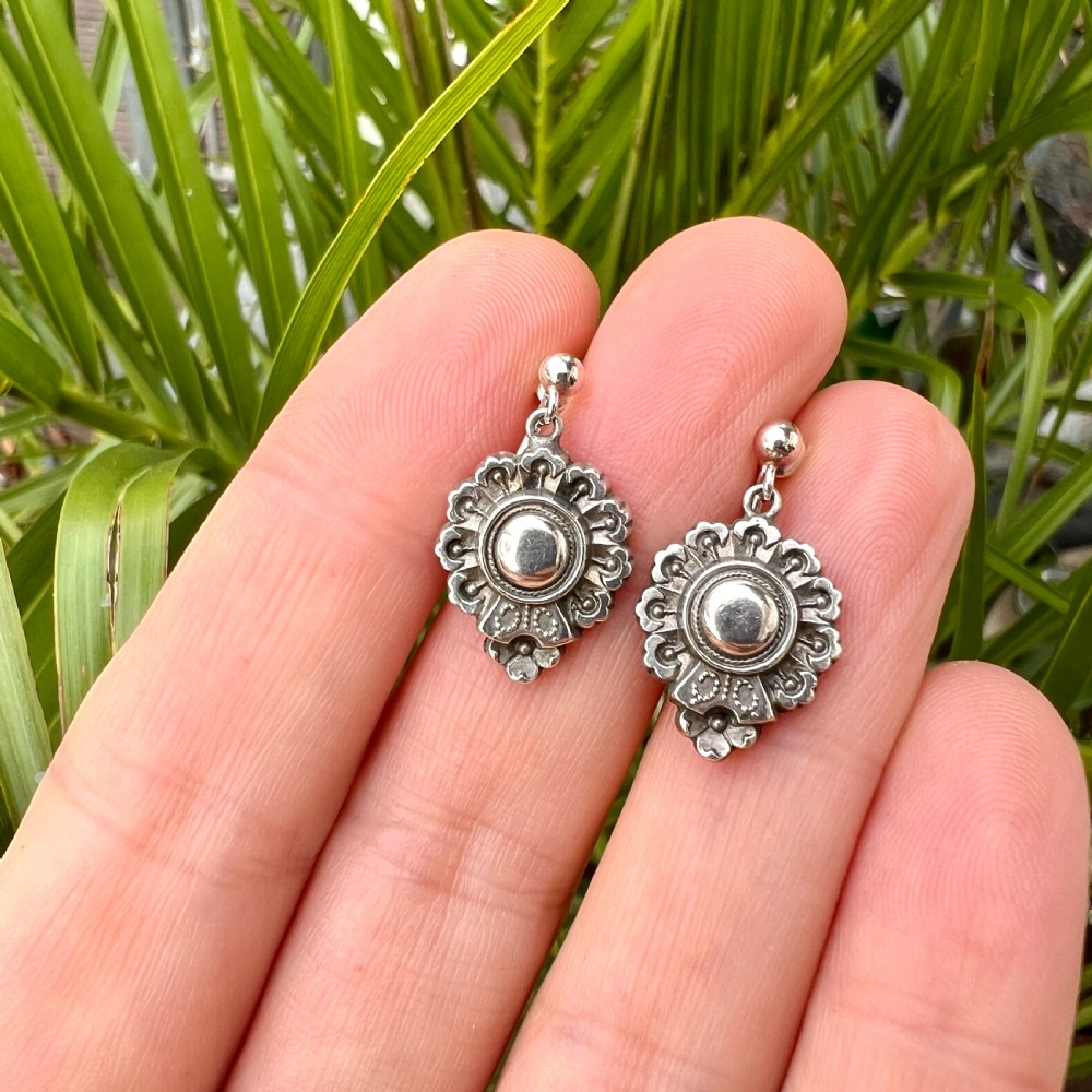 A pair of silver Victorian Aesthetic Era drop earrings featuring a sunburst motif with beaded detailing and screwback fastenings. View VI