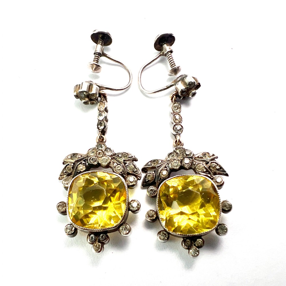 A pair of Victorian silver drop earrings featuring cushion-cut yellow citrine paste stones surrounded by foliate settings with clear glass accents. View III