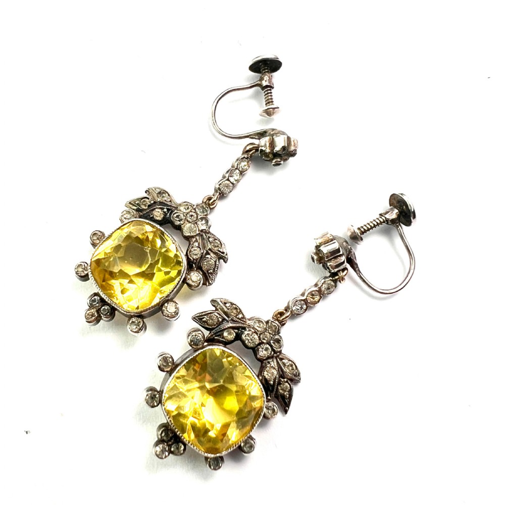A pair of Victorian silver drop earrings featuring cushion-cut yellow citrine paste stones surrounded by foliate settings with clear glass accents. View VI