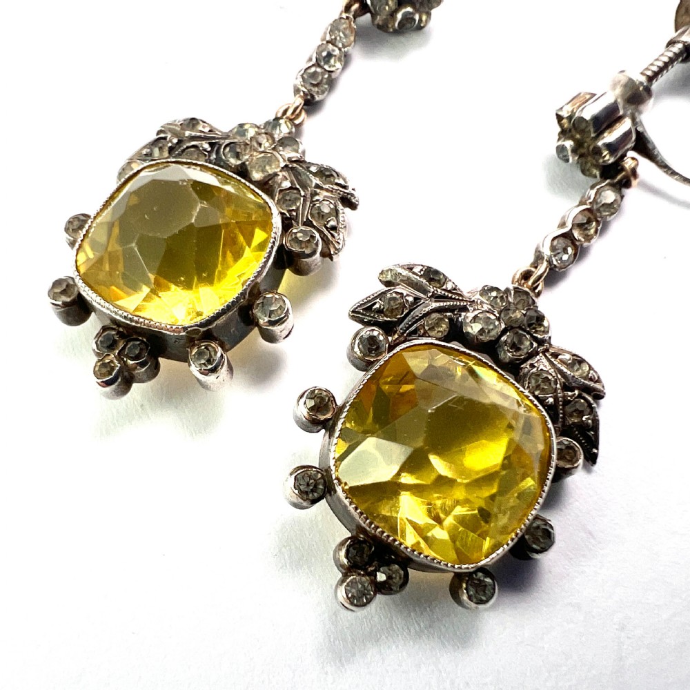 A pair of Victorian silver drop earrings featuring cushion-cut yellow citrine paste stones surrounded by foliate settings with clear glass accents. View VII