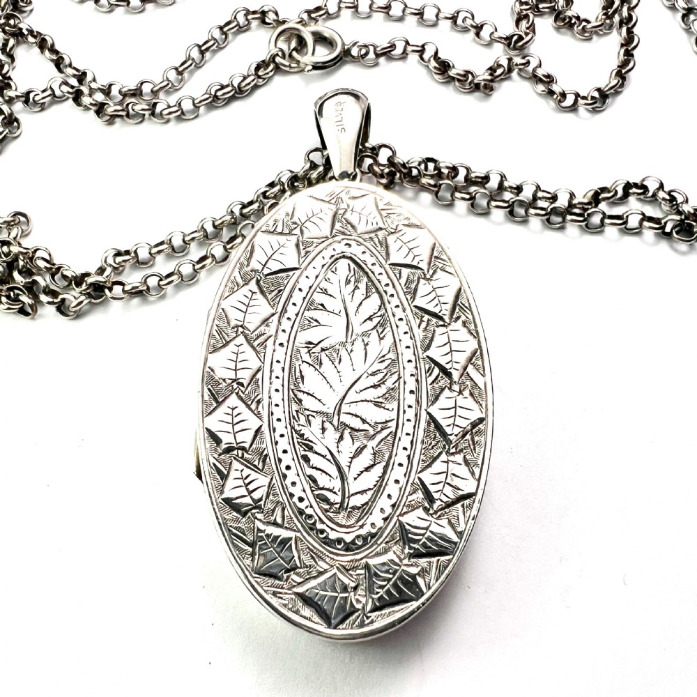 A large Victorian oval sterling silver locket with intricate foliate engraving, attached to a heavy belcher chain. View III
