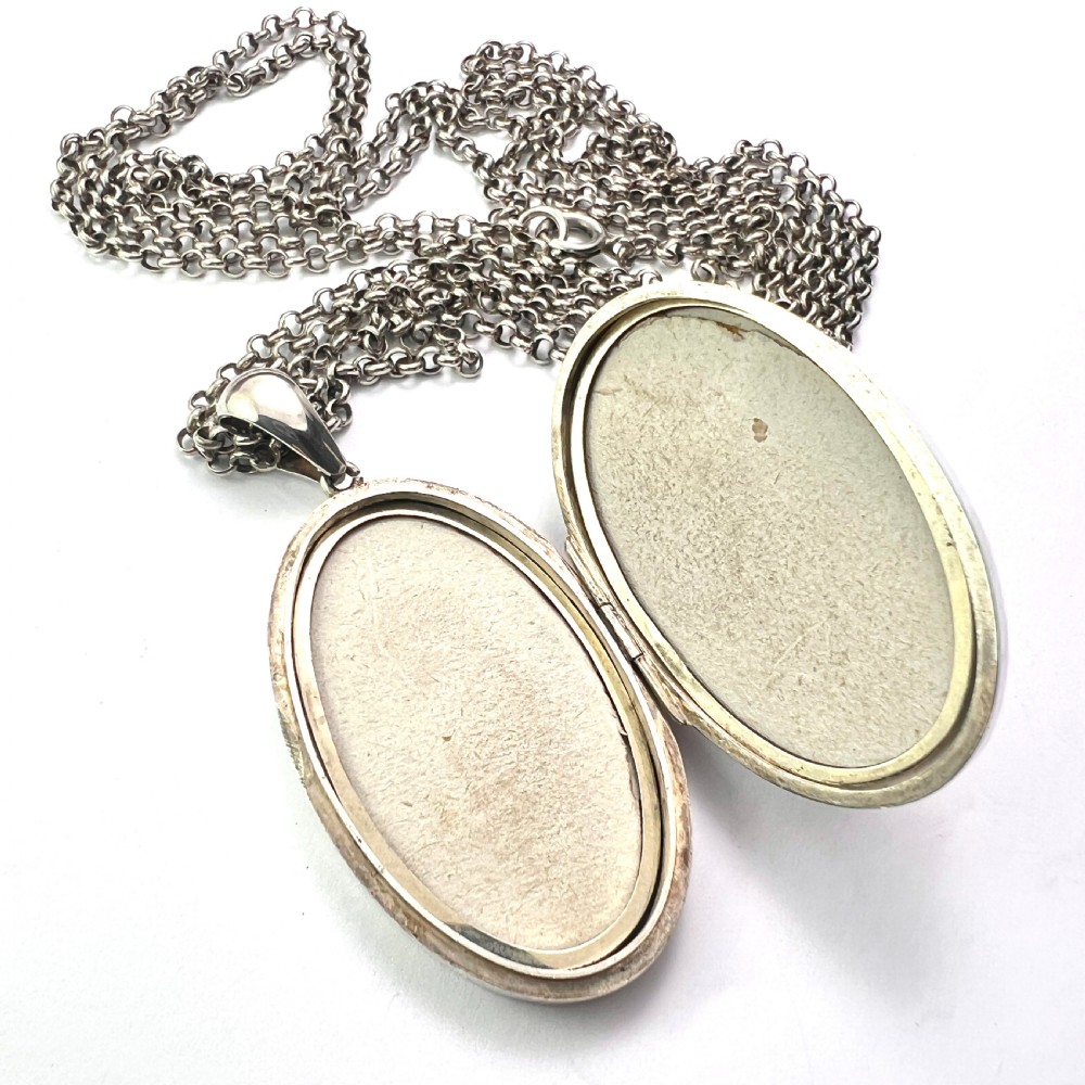 A large Victorian oval sterling silver locket with intricate foliate engraving, attached to a heavy belcher chain. View VII