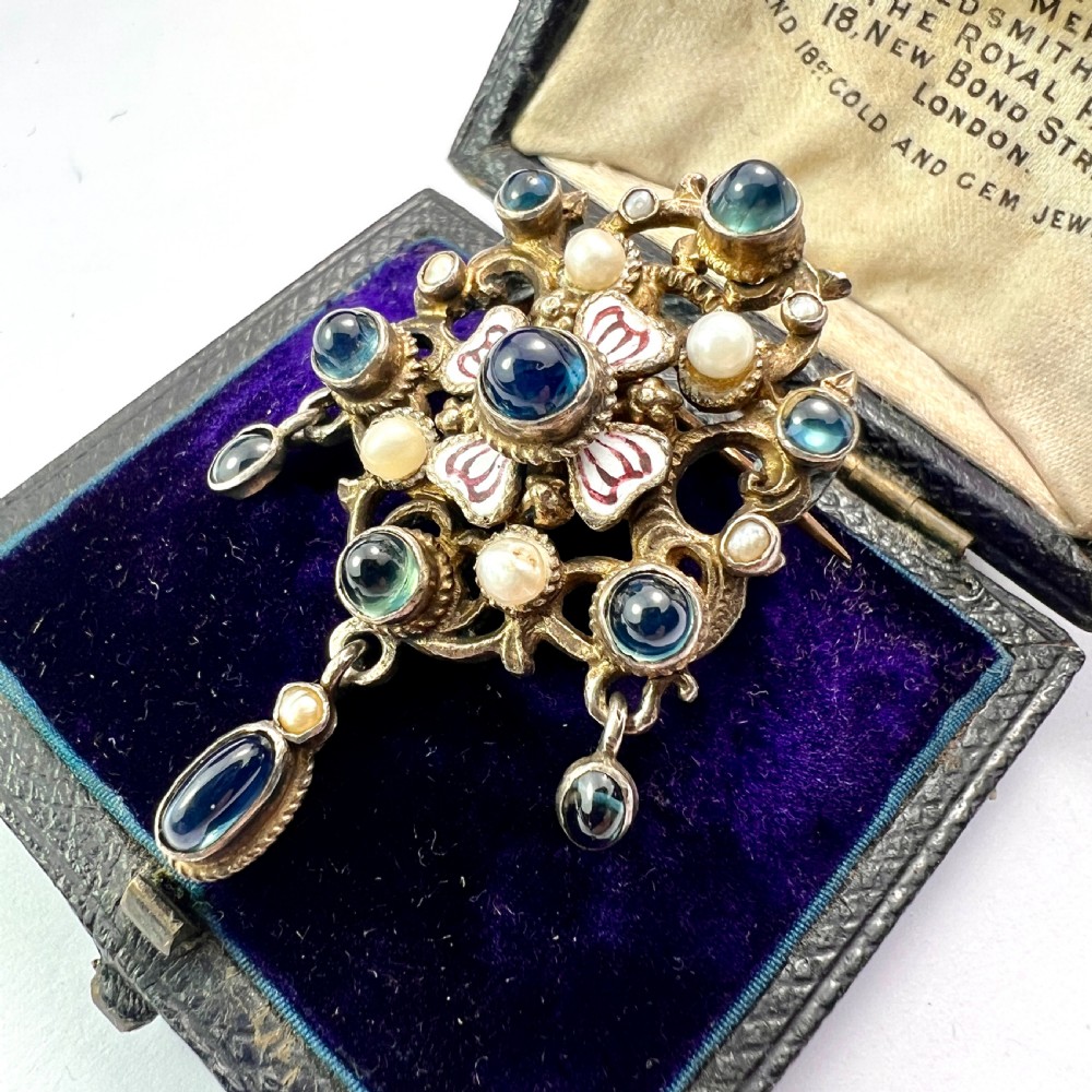 An Austro-Hungarian silver-gilt brooch decorated with blue cabochons, seed pearls, polychrome enamel, and a dangling teardrop pendant. View II