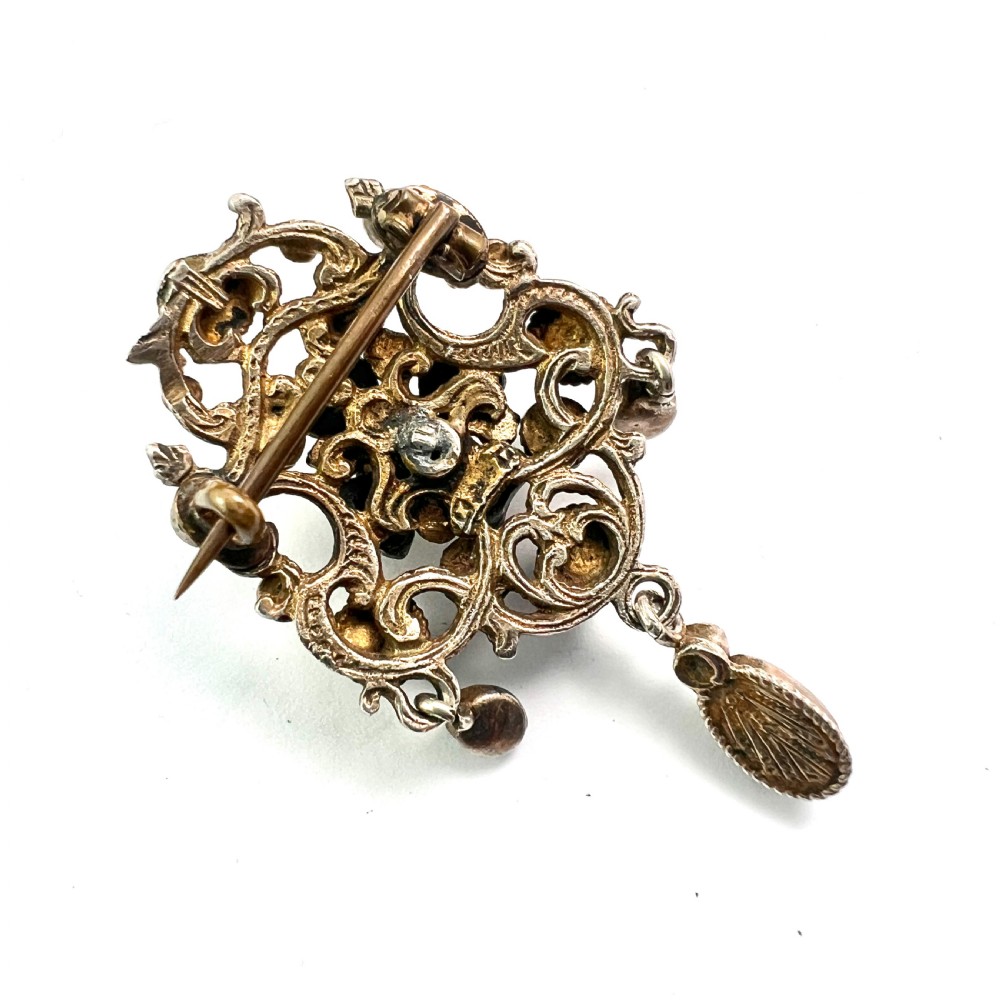 An Austro-Hungarian silver-gilt brooch decorated with blue cabochons, seed pearls, polychrome enamel, and a dangling teardrop pendant. View VI