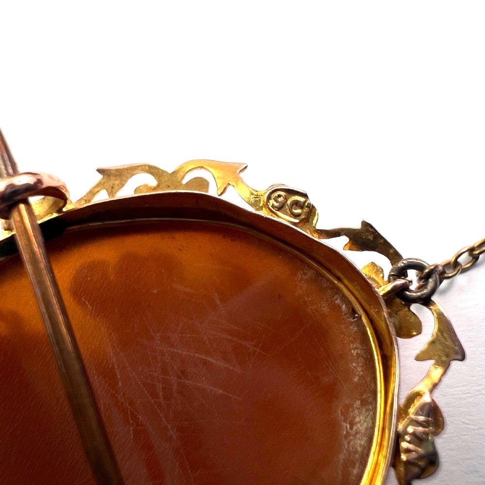 An oval Victorian 9ct gold brooch featuring a white carved shell cameo of a classical female profile set within an ornate openwork scroll frame with an attached safety pin. View VIII