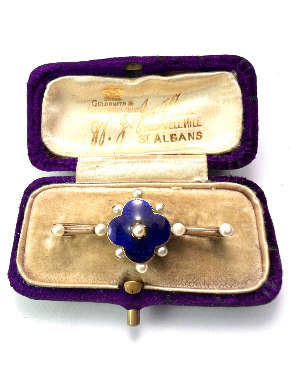 An Edwardian gold bar brooch featuring a central quatrefoil motif decorated in cobalt blue guilloche enamel and surrounded by pearls. View II