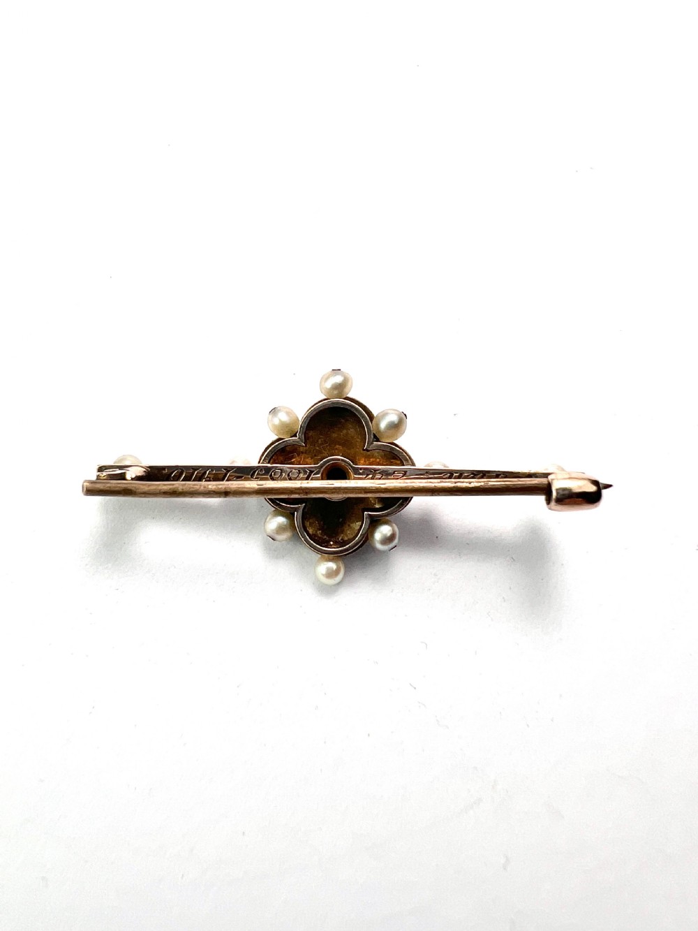 An Edwardian gold bar brooch featuring a central quatrefoil motif decorated in cobalt blue guilloche enamel and surrounded by pearls. View V