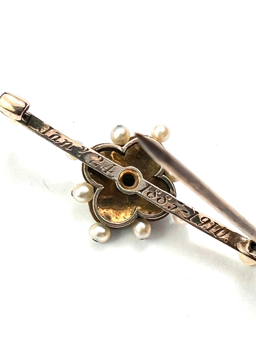 An Edwardian gold bar brooch featuring a central quatrefoil motif decorated in cobalt blue guilloche enamel and surrounded by pearls. View VI
