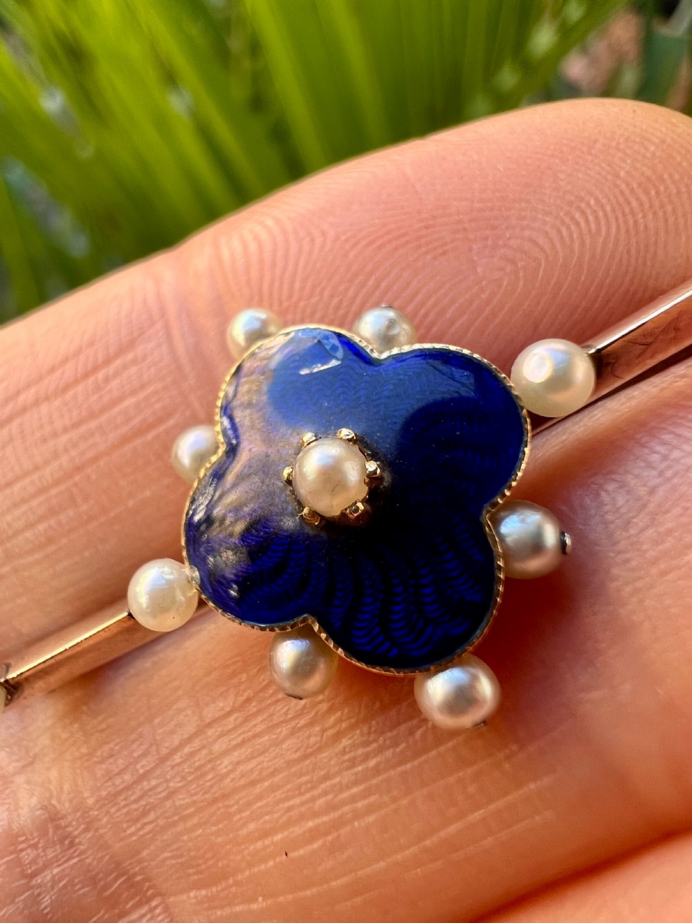 An Edwardian gold bar brooch featuring a central quatrefoil motif decorated in cobalt blue guilloche enamel and surrounded by pearls. View XI