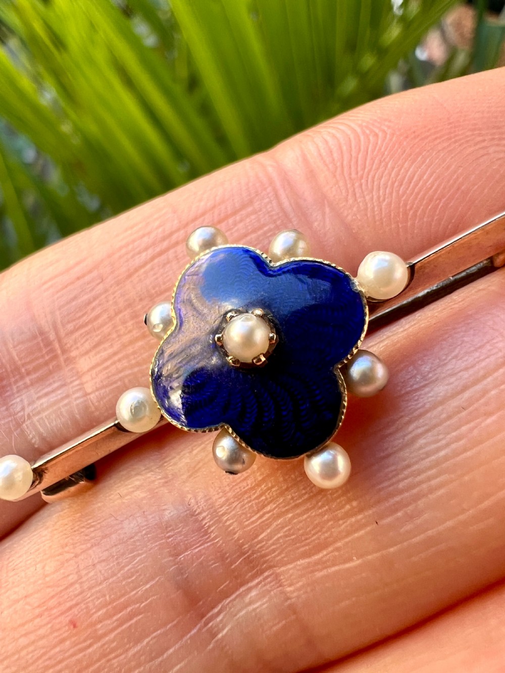 An Edwardian gold bar brooch featuring a central quatrefoil motif decorated in cobalt blue guilloche enamel and surrounded by pearls. View XII