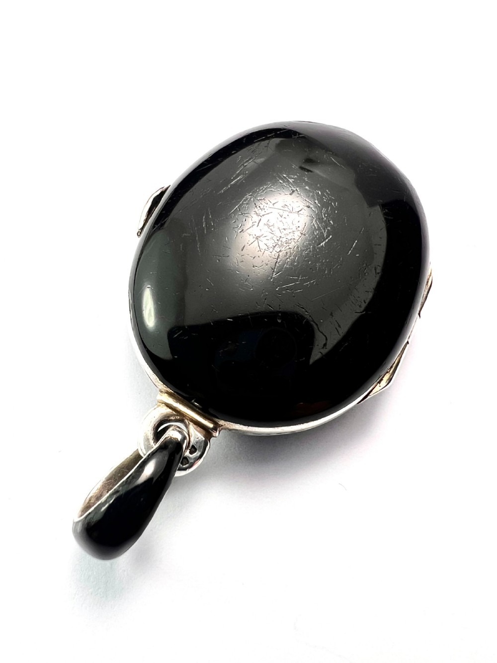 An oval Victorian silver locket rendered in black enamel with an intricate marcasite-set AEI monogram on the front surface. View V