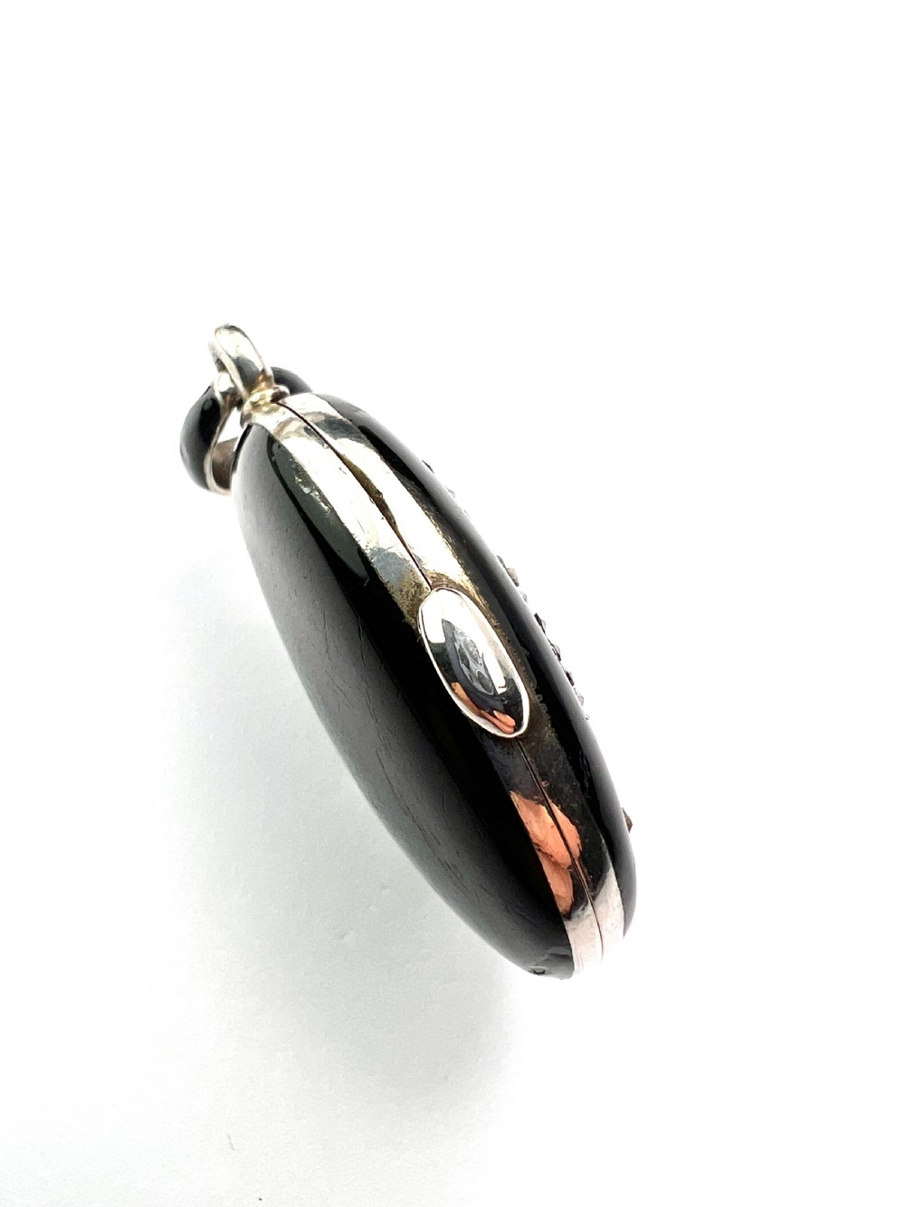 An oval Victorian silver locket rendered in black enamel with an intricate marcasite-set AEI monogram on the front surface. View VI