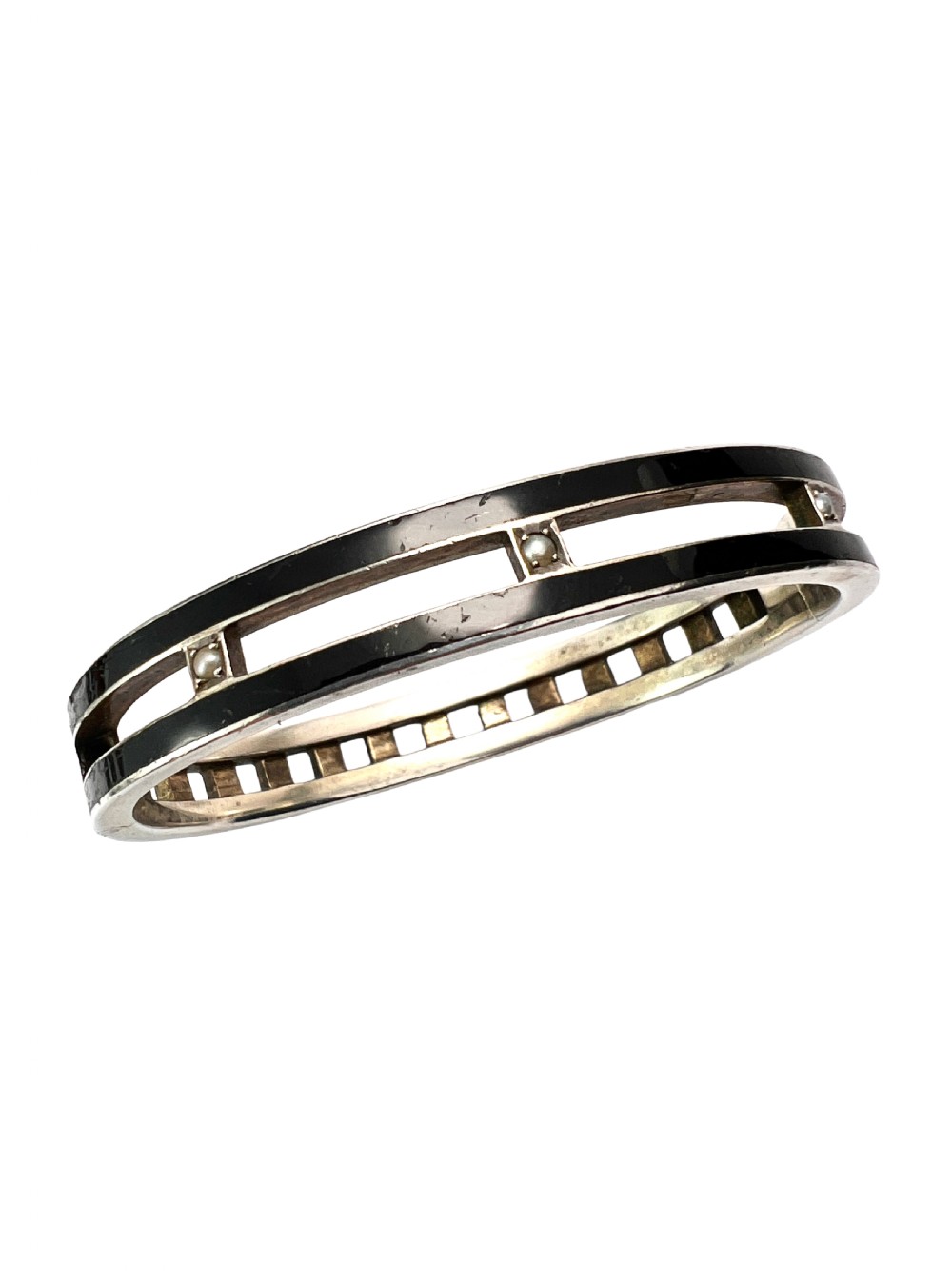 An antique Austro-Hungarian silver hinged bangle featuring black enamel borders and an openwork centre set with seed pearls. View II