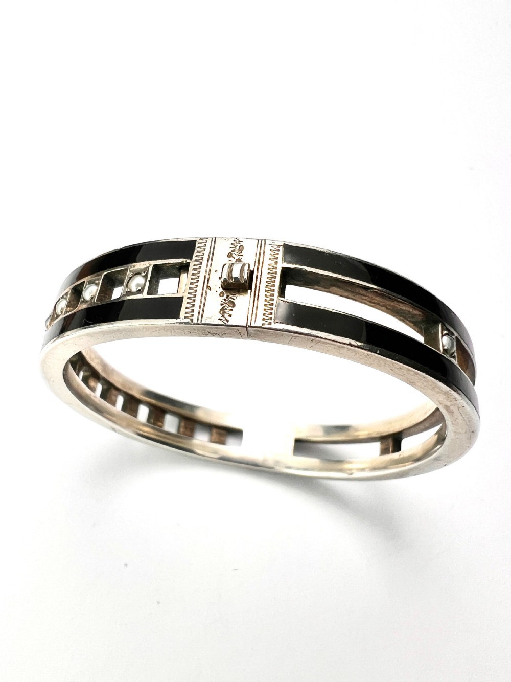 An antique Austro-Hungarian silver hinged bangle featuring black enamel borders and an openwork centre set with seed pearls. View III