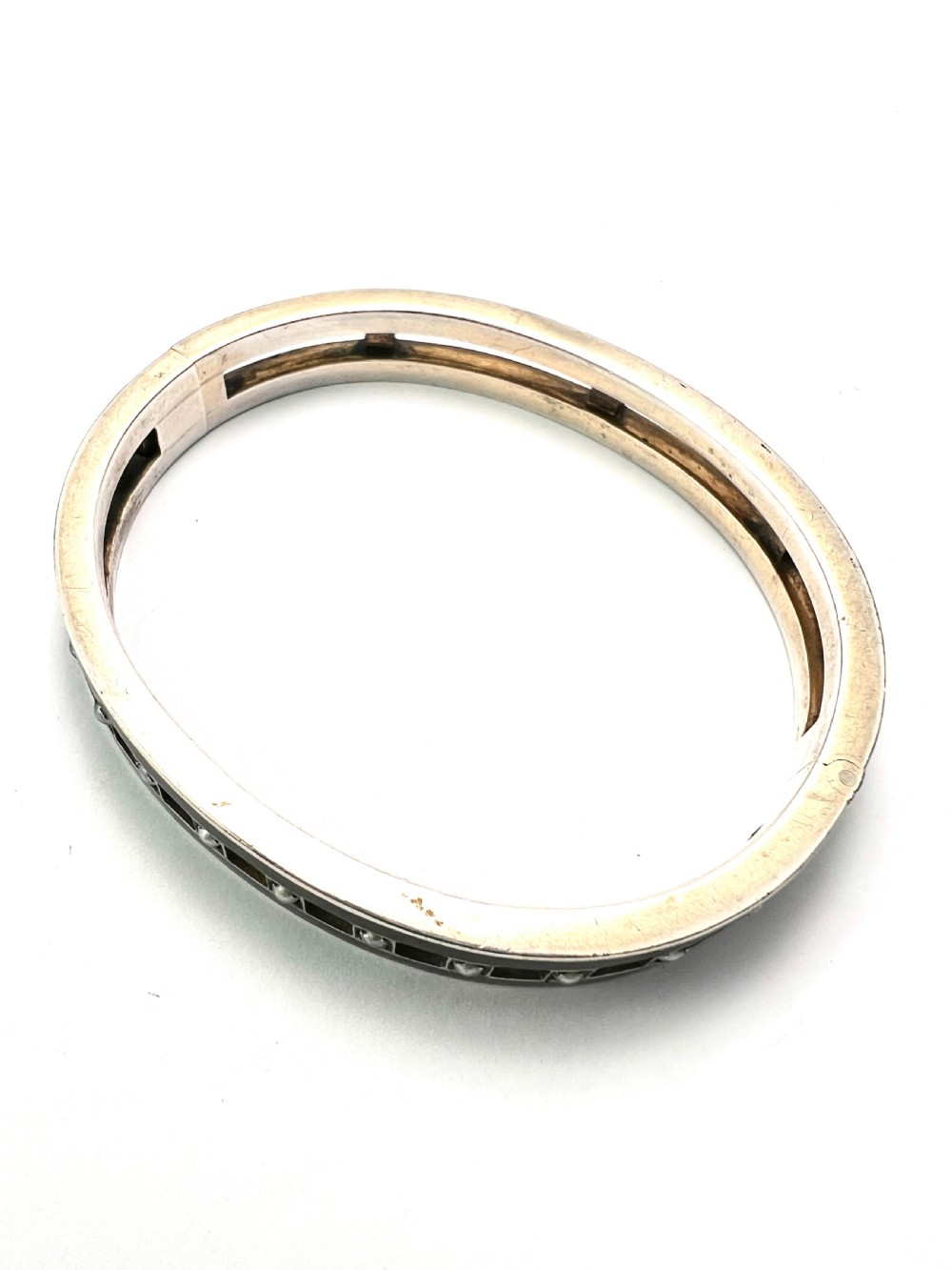 An antique Austro-Hungarian silver hinged bangle featuring black enamel borders and an openwork centre set with seed pearls. View V