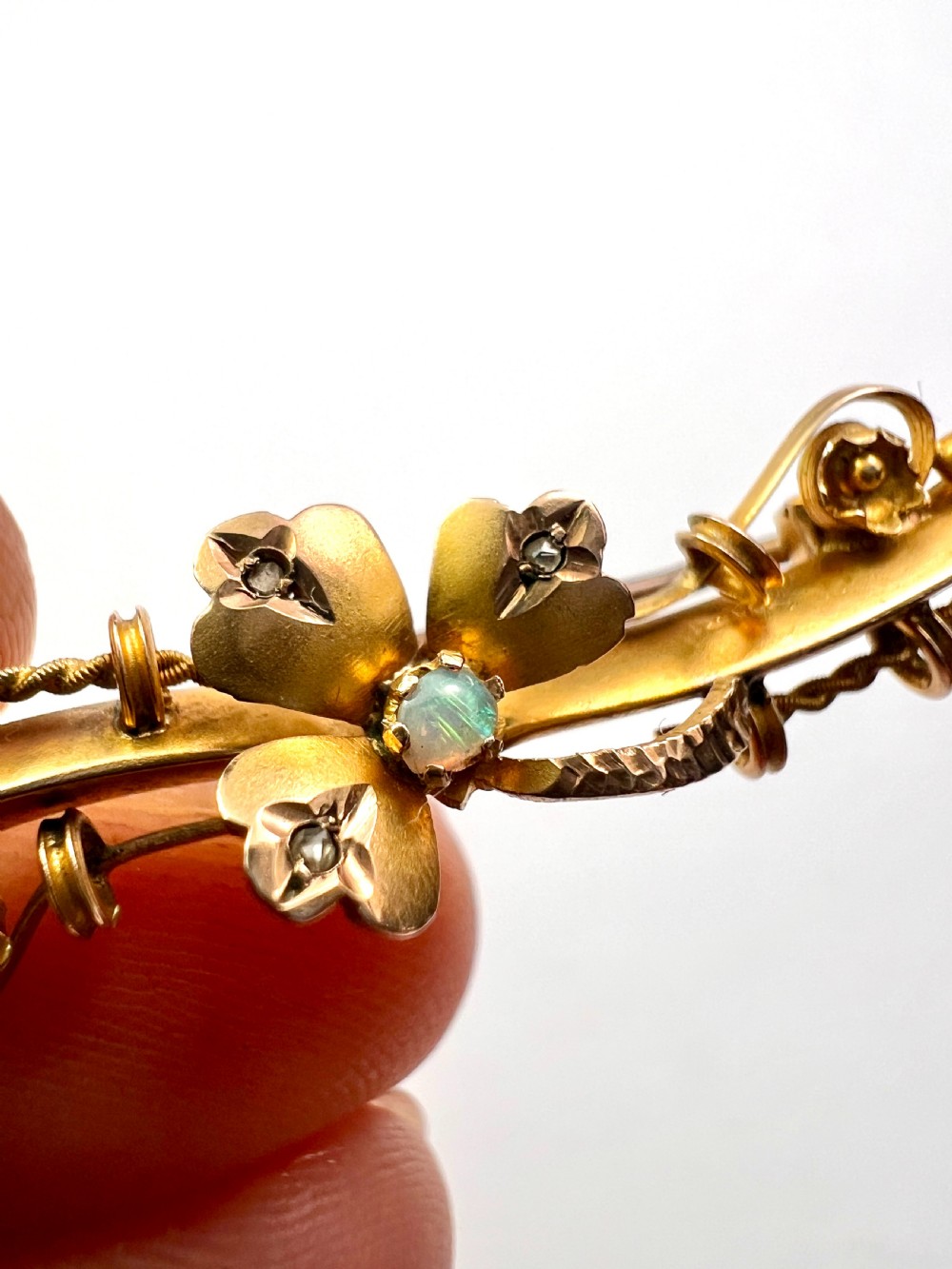 A Victorian 9ct yellow gold bar brooch featuring a central three-leaf clover set with a cabochon opal and accent diamonds. View VIII