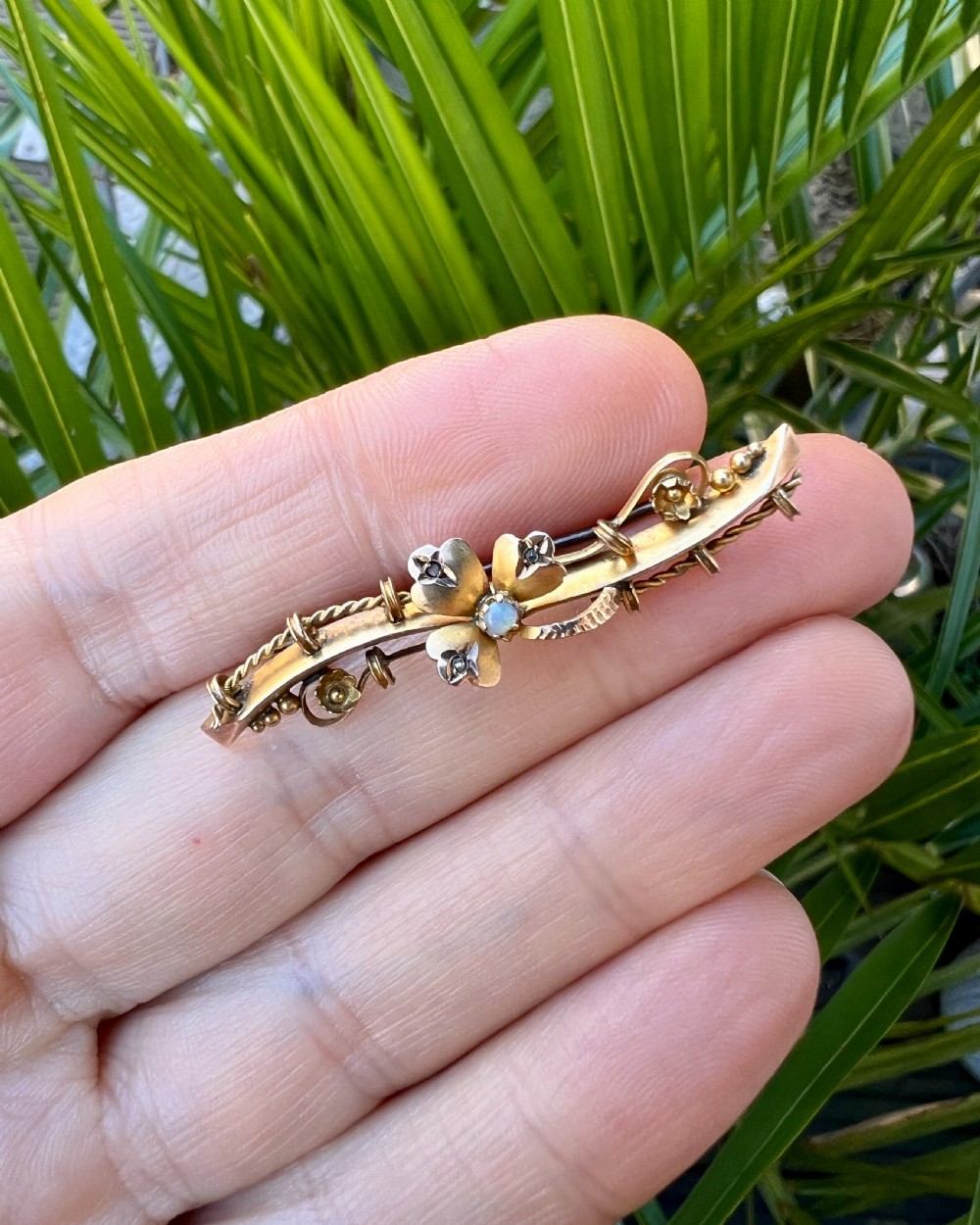 A Victorian 9ct yellow gold bar brooch featuring a central three-leaf clover set with a cabochon opal and accent diamonds. View XI