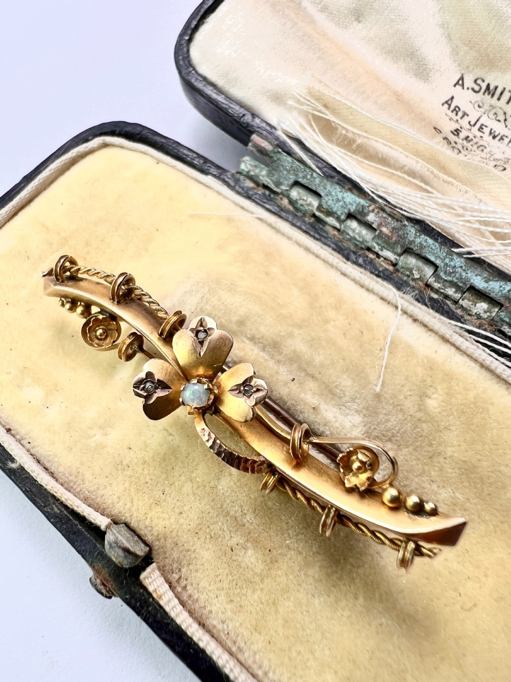 A Victorian 9ct yellow gold bar brooch featuring a central three-leaf clover set with a cabochon opal and accent diamonds. View XIII