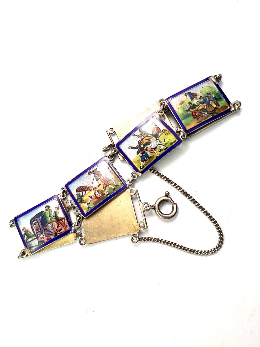 A vintage silver link bracelet featuring rectangular panels decorated with hand-painted miniature genre scenes bordered in cobalt blue enamel. View III