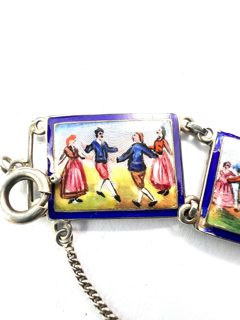 A vintage silver link bracelet featuring rectangular panels decorated with hand-painted miniature genre scenes bordered in cobalt blue enamel. View XIII