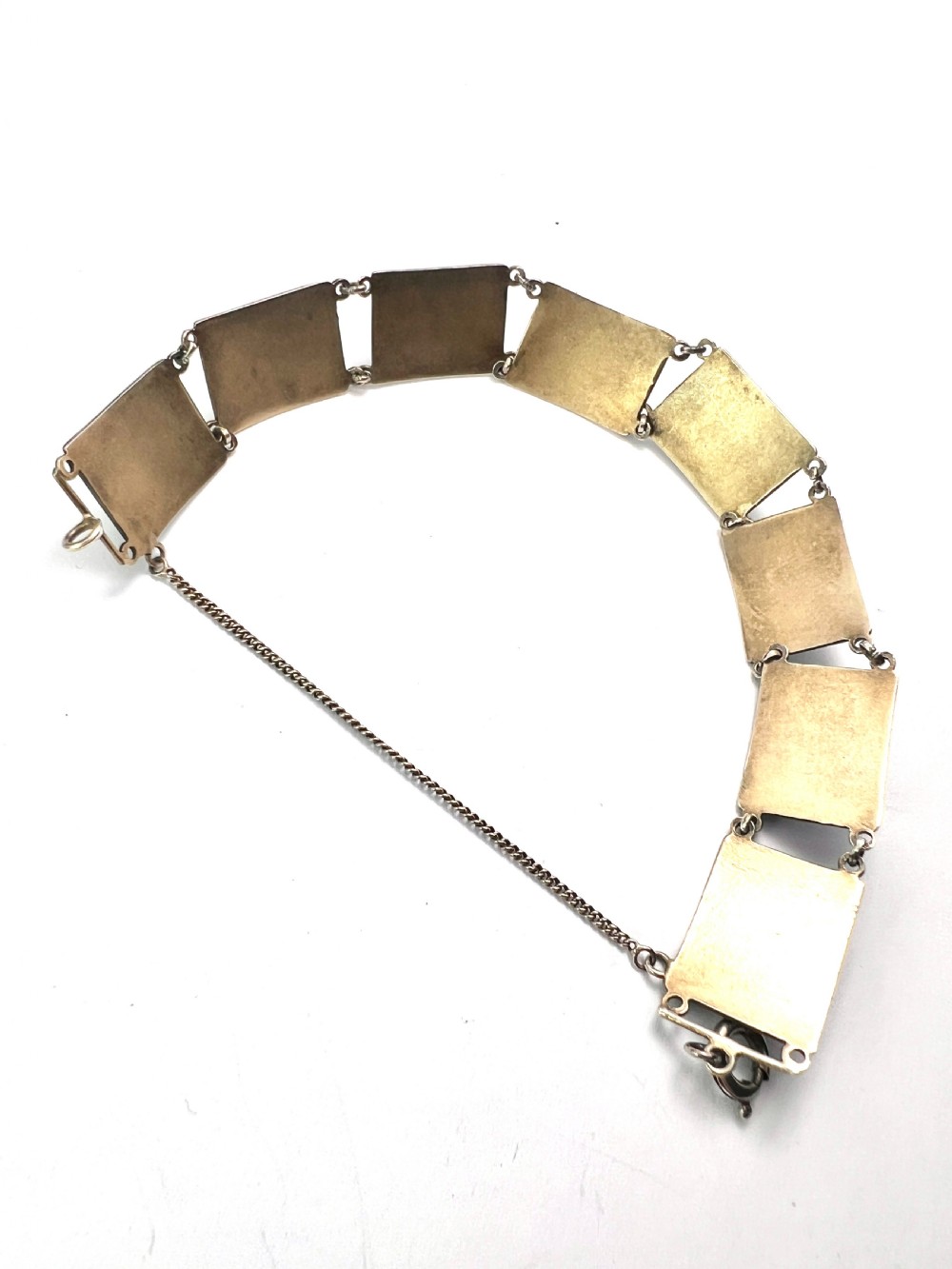 A vintage silver link bracelet featuring rectangular panels decorated with hand-painted miniature genre scenes bordered in cobalt blue enamel. View XIV