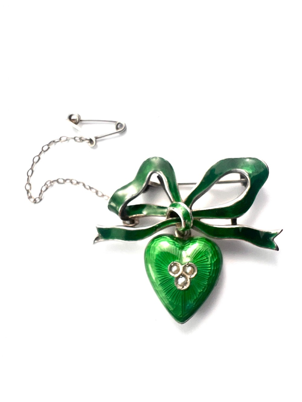 An antique silver brooch featuring a green translucent enamel ribbon bow with a hanging green enamel heart drop set with three small seed pearls. View II