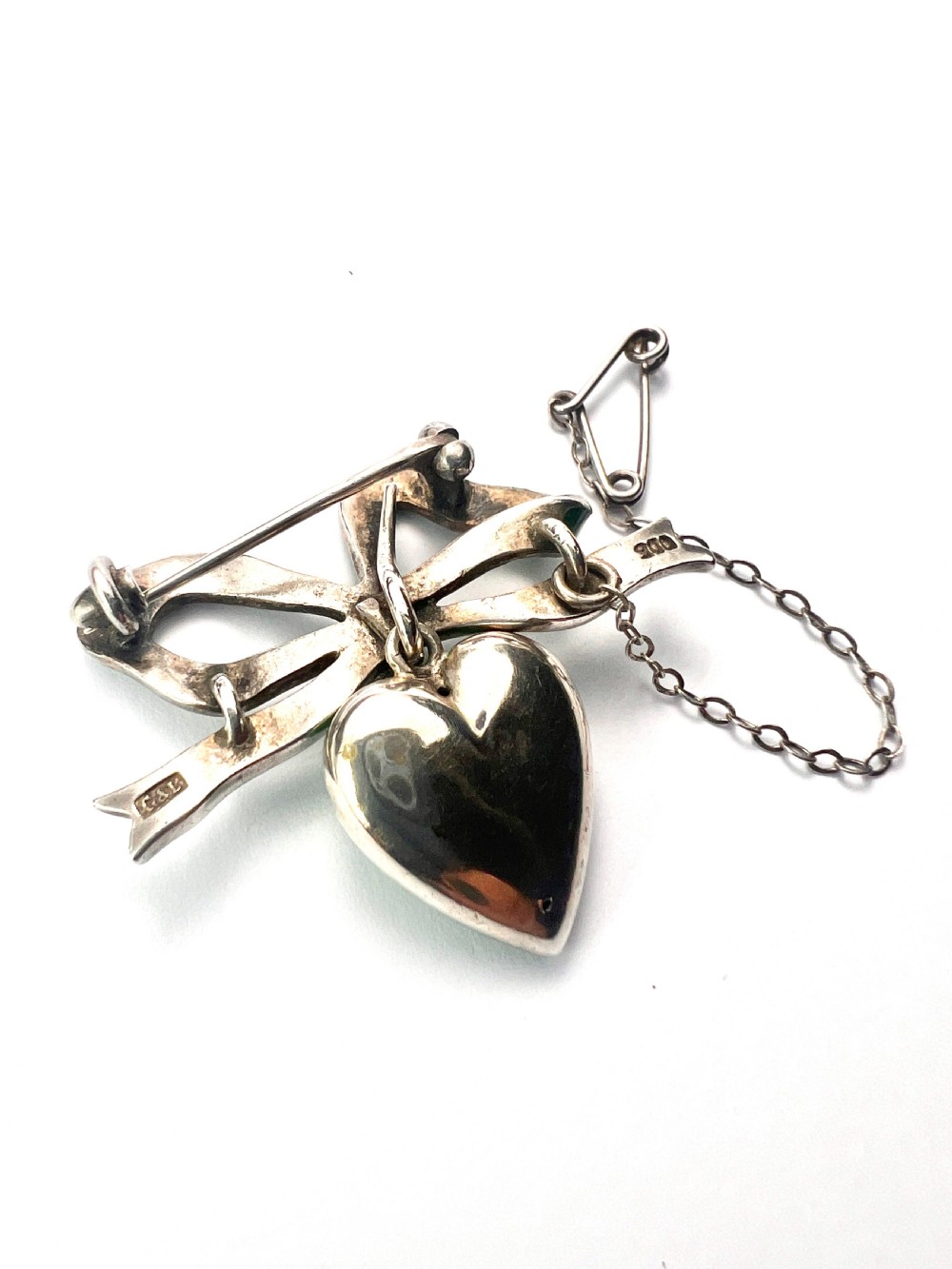 An antique silver brooch featuring a green translucent enamel ribbon bow with a hanging green enamel heart drop set with three small seed pearls. View VI