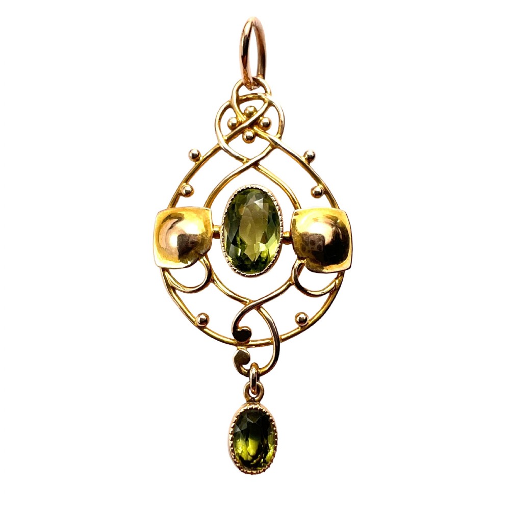An Edwardian 15ct gold Art Nouveau openwork pendant set with two faceted green peridot gemstones.