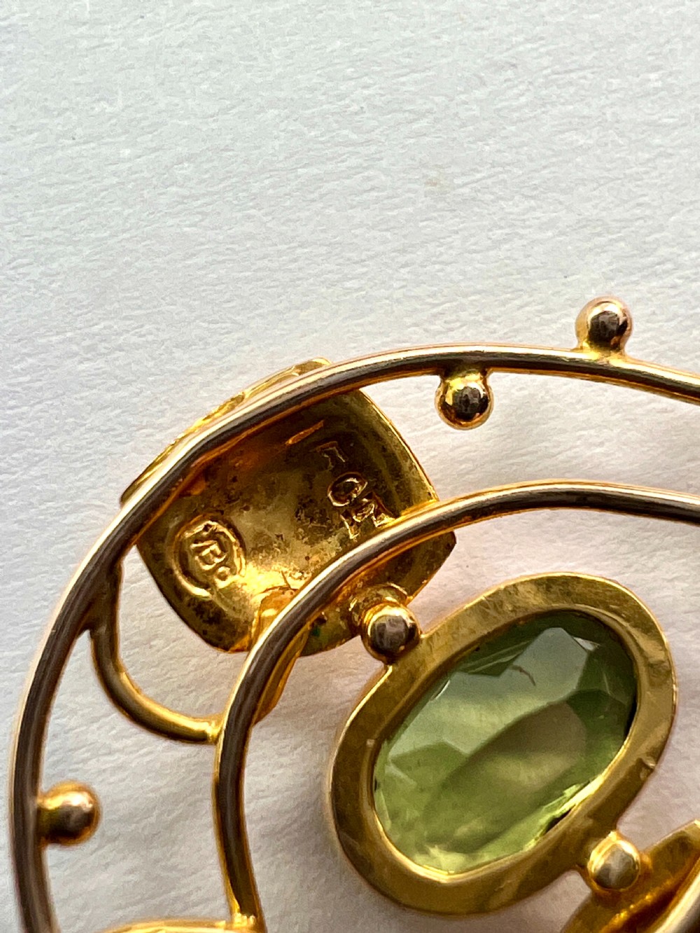 An Edwardian 15ct gold Art Nouveau openwork pendant set with two faceted green peridot gemstones. View V