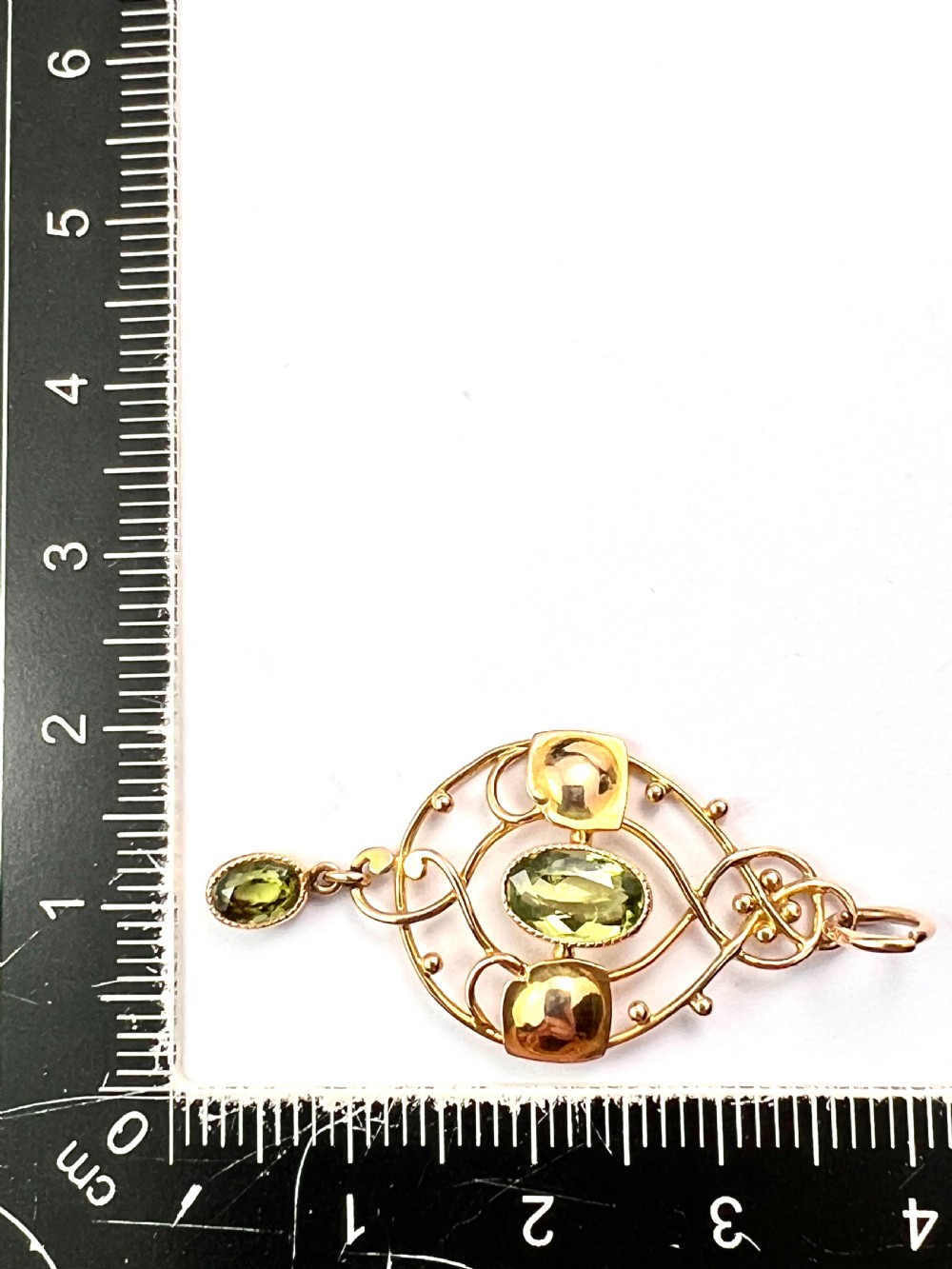 An Edwardian 15ct gold Art Nouveau openwork pendant set with two faceted green peridot gemstones. View VII