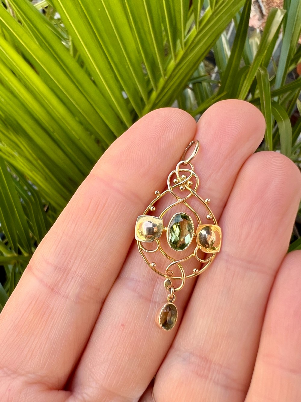 An Edwardian 15ct gold Art Nouveau openwork pendant set with two faceted green peridot gemstones. View VIII