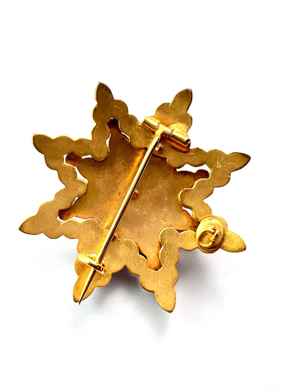 A multi-tiered starburst brooch closely set with faceted deep red rose-cut garnets in a gilded claw setting. View VII