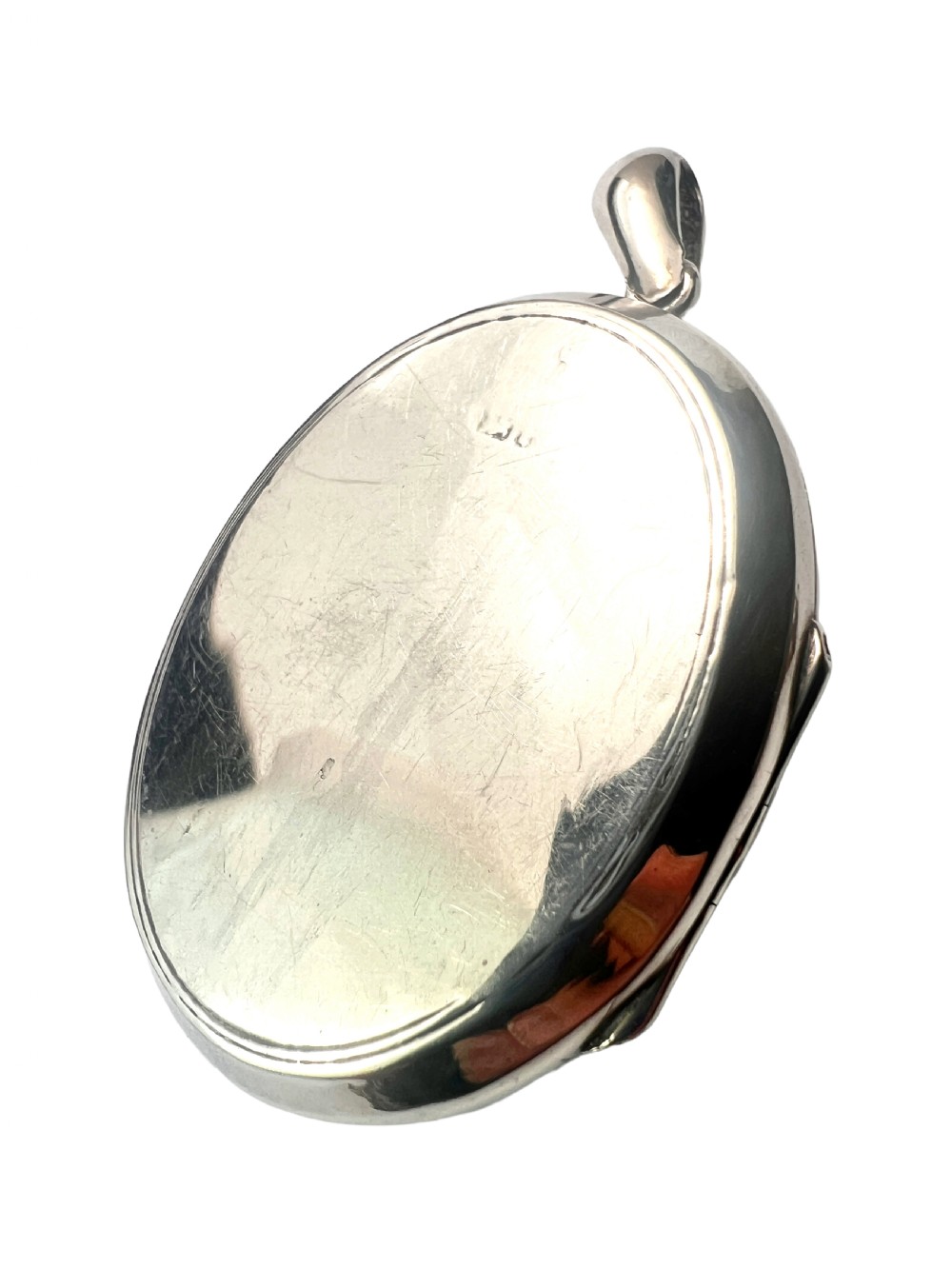 A large oval silver locket featuring a central raised crucifix motif draped with sculpted ivy foliage, fitted with an oval bail at the top. View IV