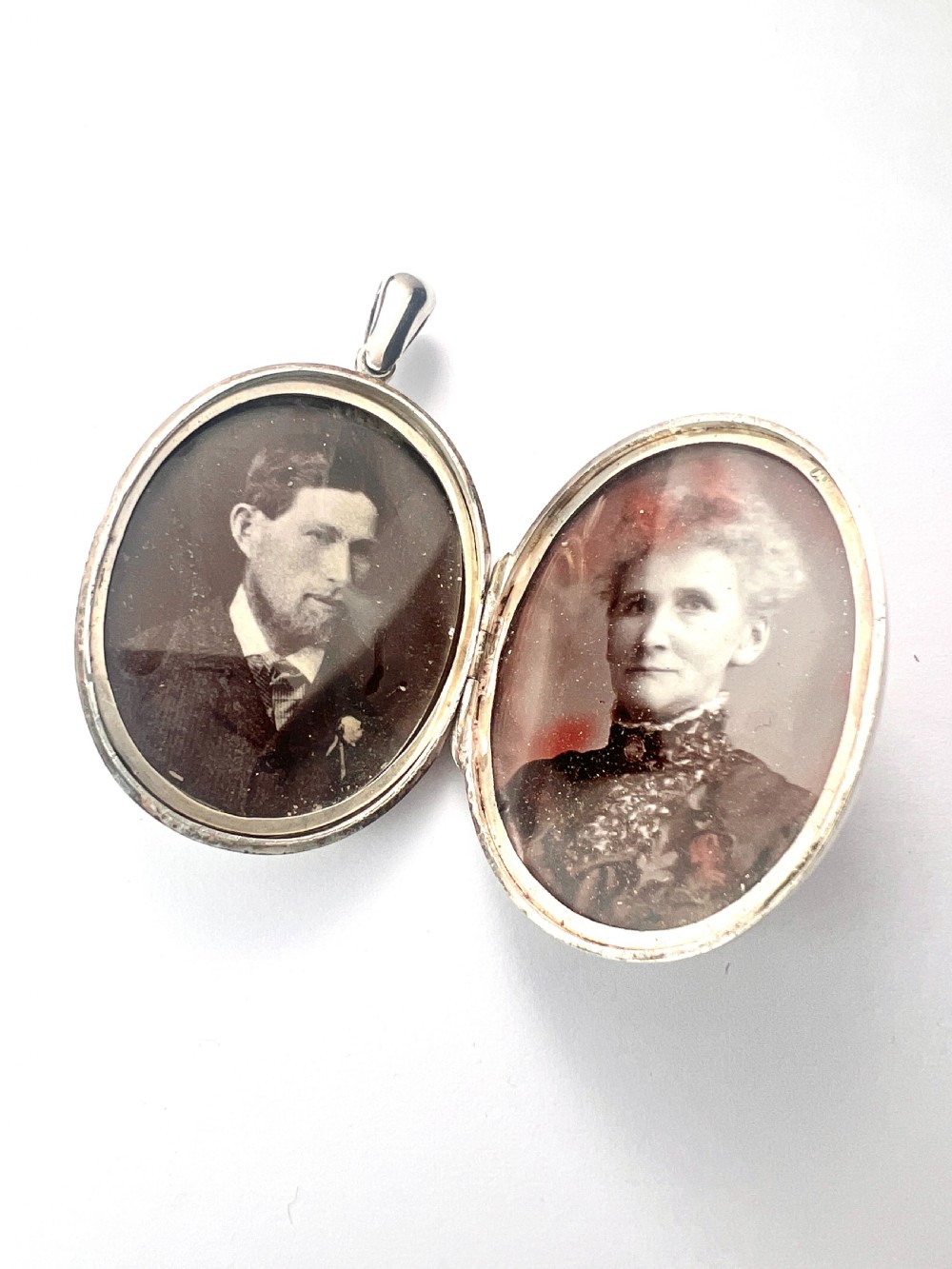 A large oval silver locket featuring a central raised crucifix motif draped with sculpted ivy foliage, fitted with an oval bail at the top. View V