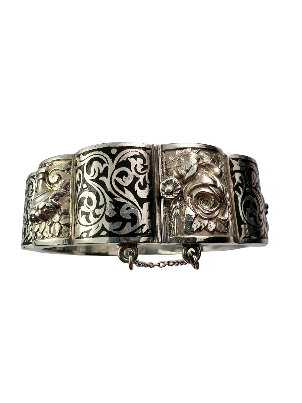 A vintage Portuguese silver hinged cuff bangle featuring engraved foliate scrollwork and corn motifs with dark niello detailing and a safety chain. View V