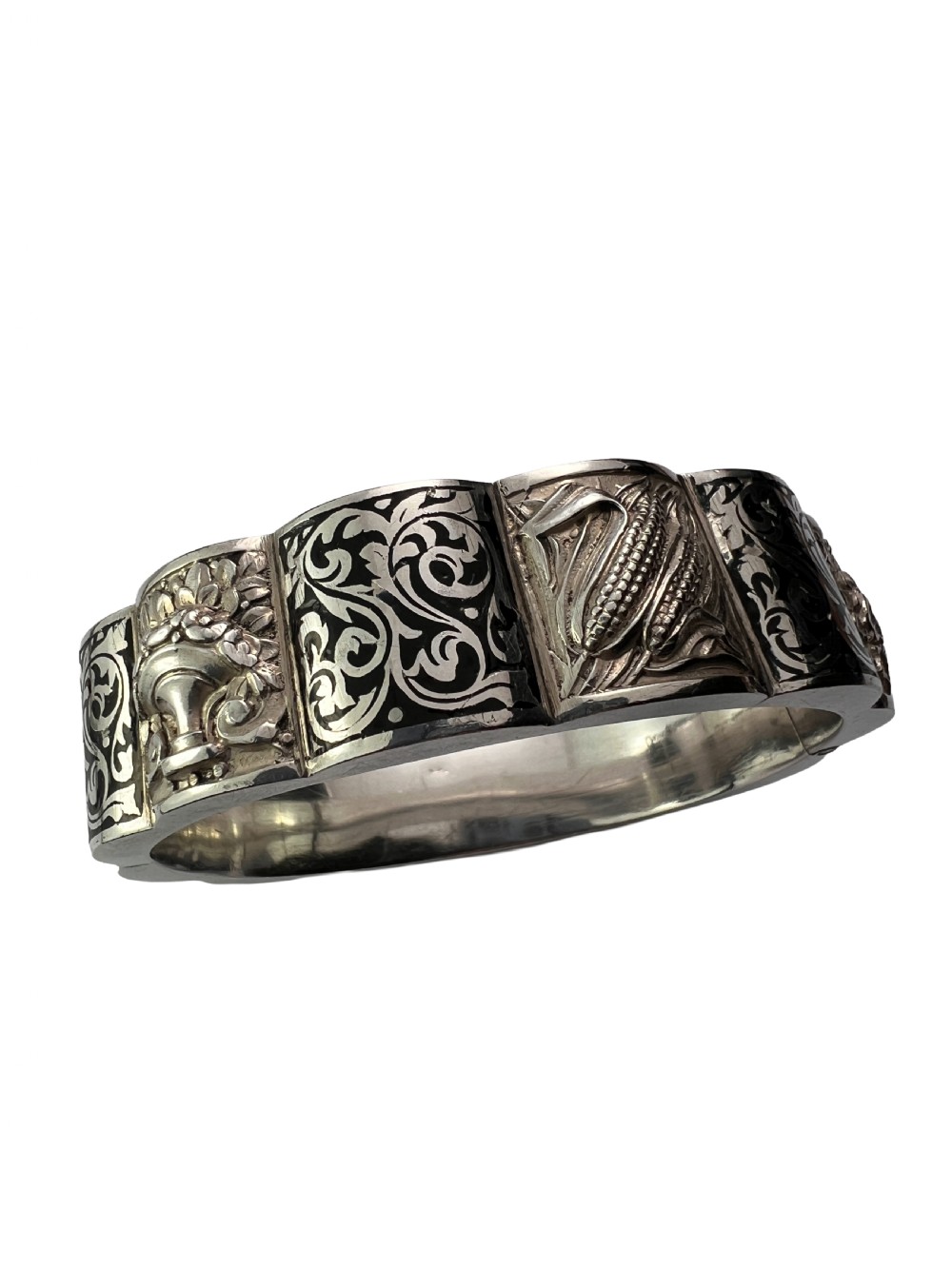 A vintage Portuguese silver hinged cuff bangle featuring engraved foliate scrollwork and corn motifs with dark niello detailing and a safety chain. View VII