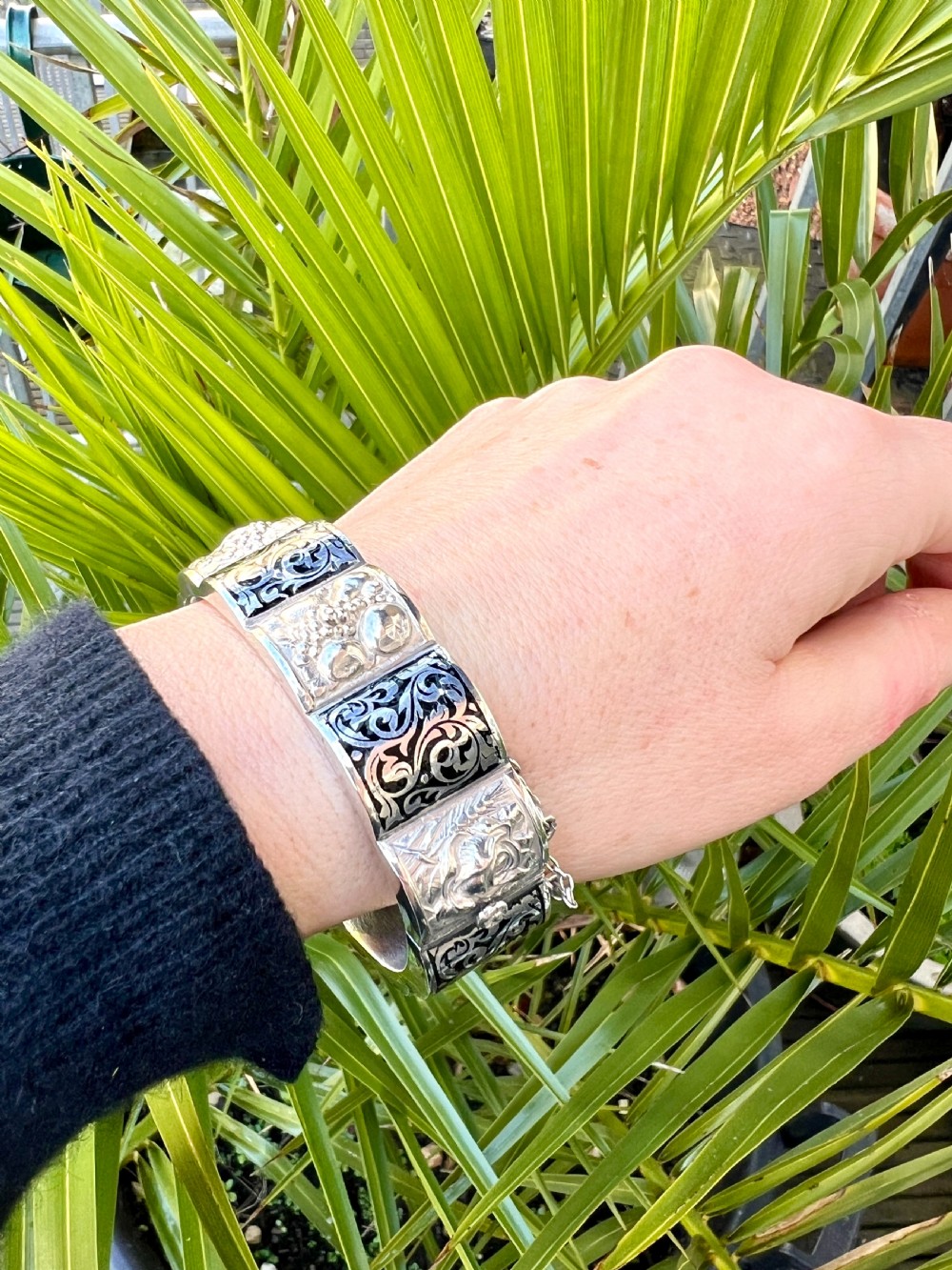 A vintage Portuguese silver hinged cuff bangle featuring engraved foliate scrollwork and corn motifs with dark niello detailing and a safety chain. View XIV