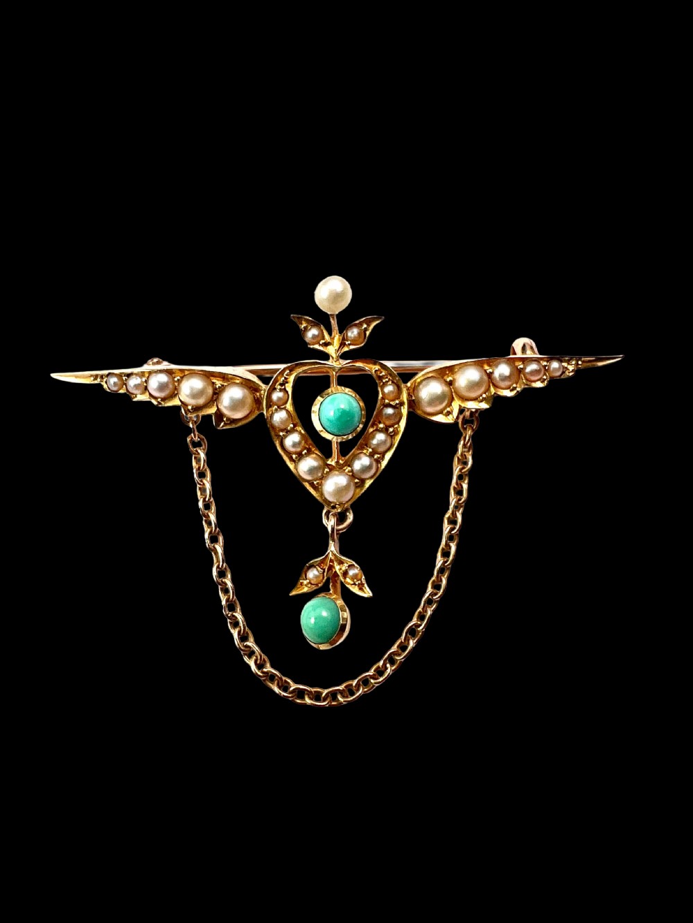 An Edwardian 15ct gold brooch featuring a winged heart motif set with seed pearls and turquoise cabochons with a draped lower chain. View III