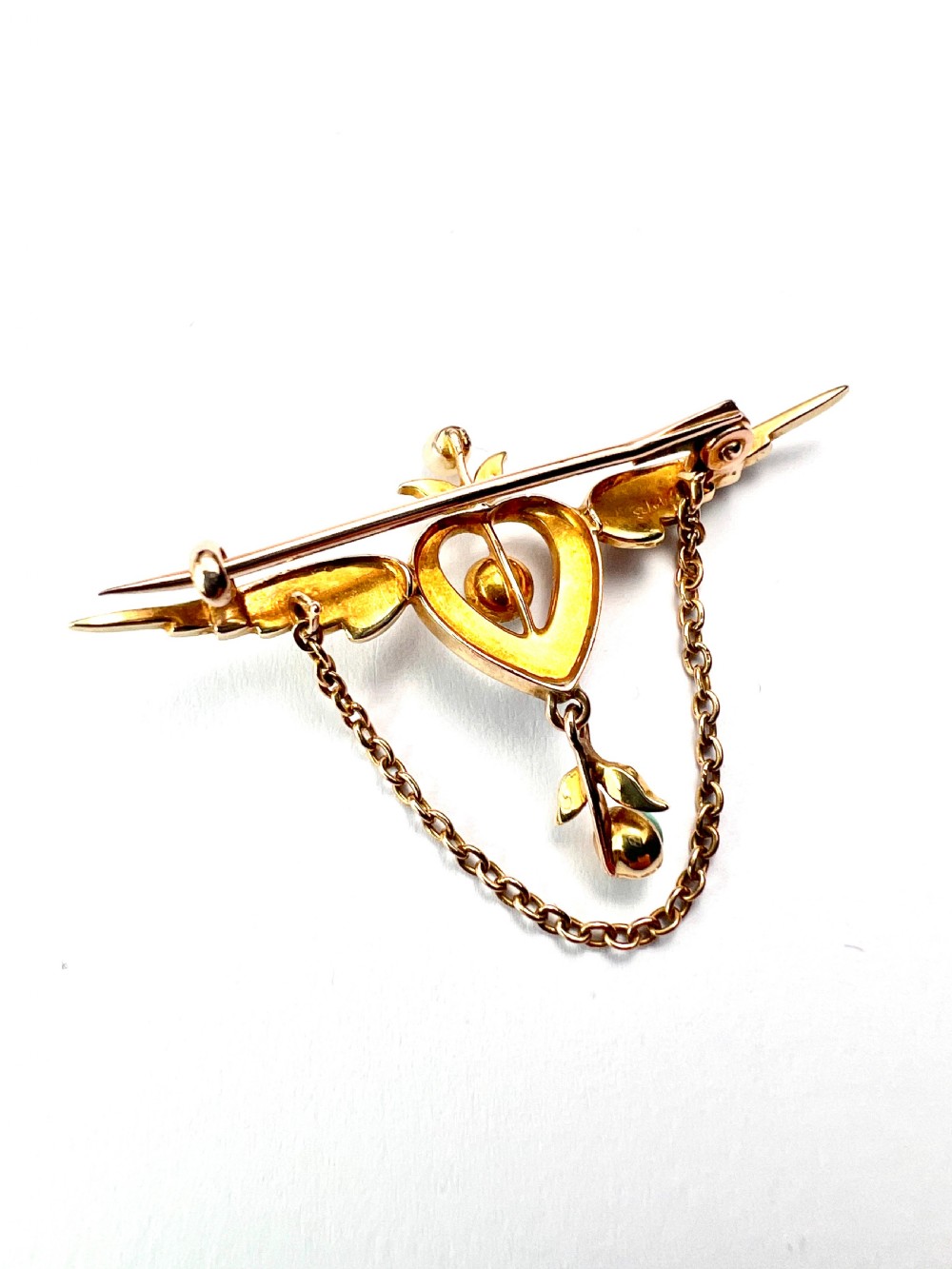 An Edwardian 15ct gold brooch featuring a winged heart motif set with seed pearls and turquoise cabochons with a draped lower chain. View VI