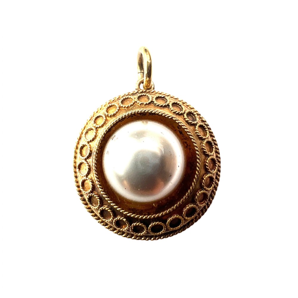 A circular Victorian yellow gold pendant featuring a large central pearl bordered by intricate filigree wirework and ropework detail.