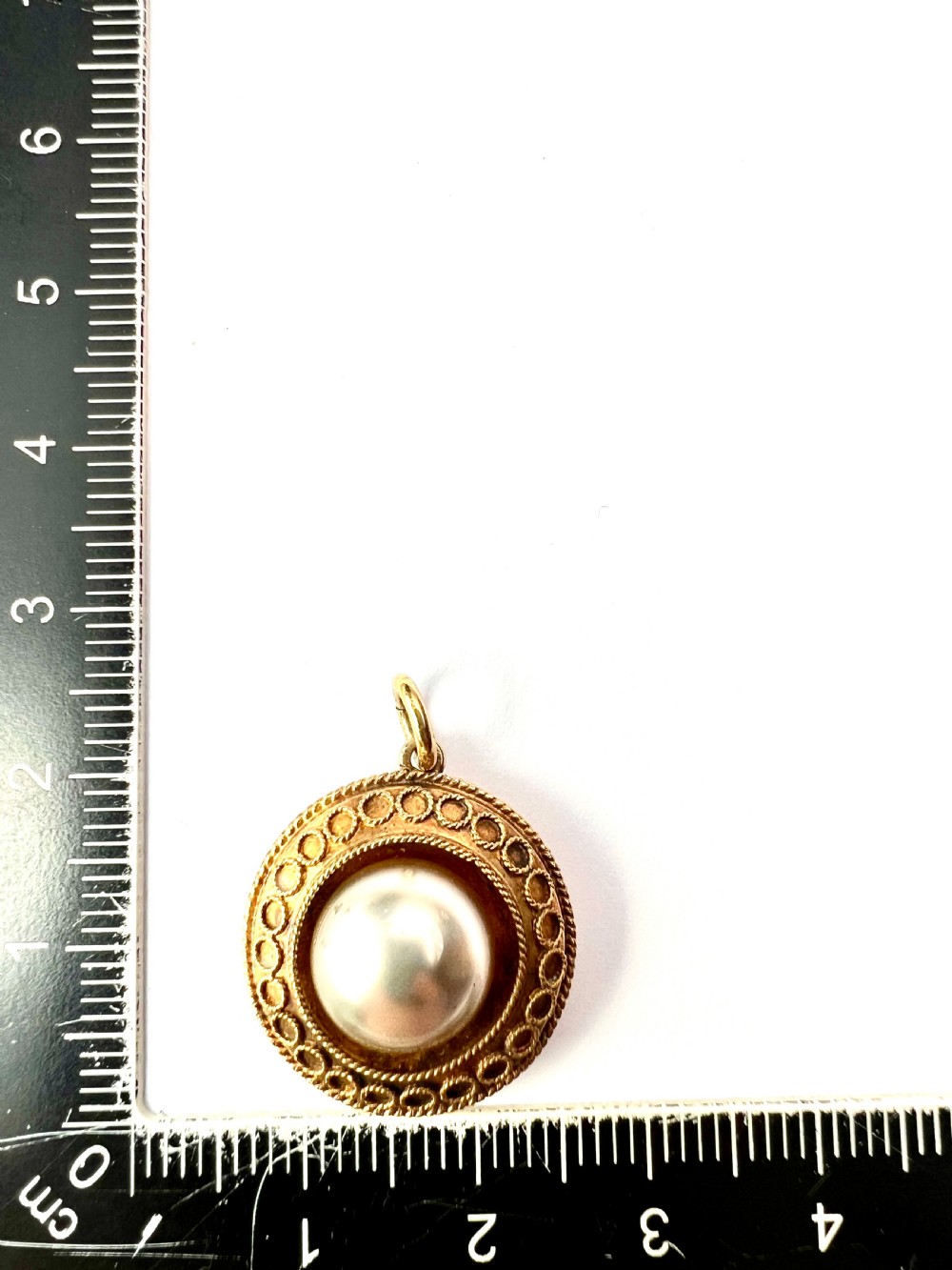 A circular Victorian yellow gold pendant featuring a large central pearl bordered by intricate filigree wirework and ropework detail. View VI