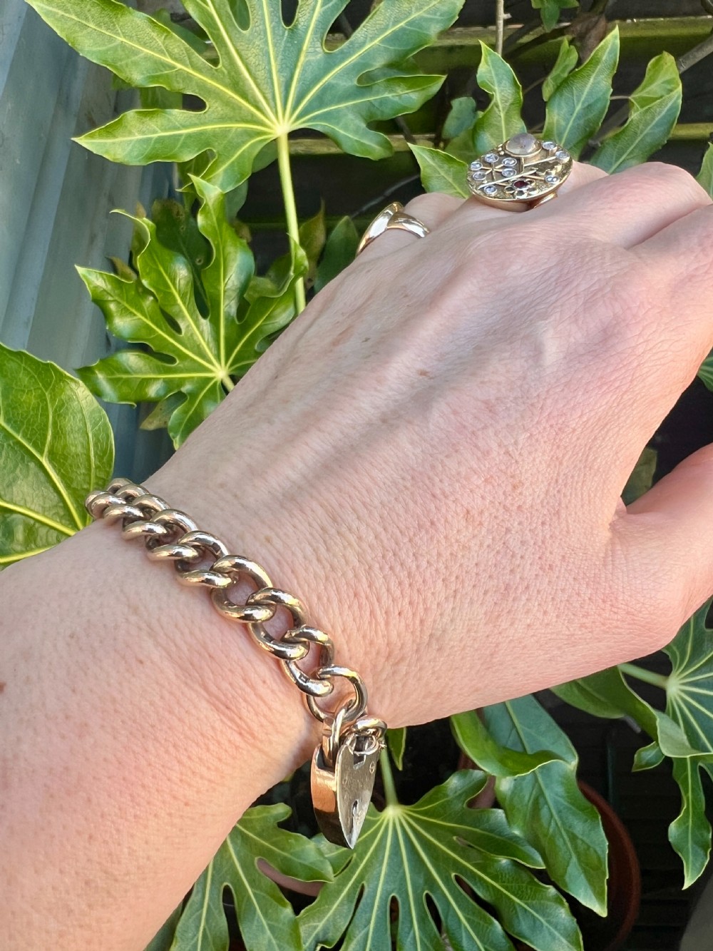 A Victorian sterling silver curb link Albert watch chain featuring a T-bar, watch key charm, and red stone swivel fob. View X