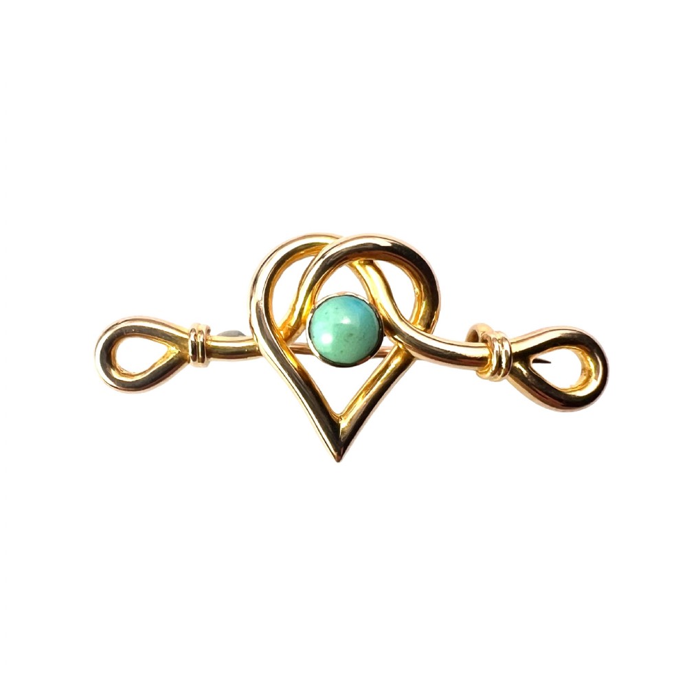 An antique 15ct yellow gold bar brooch featuring a central entwined heart motif set with a round turquoise cabochon stone.