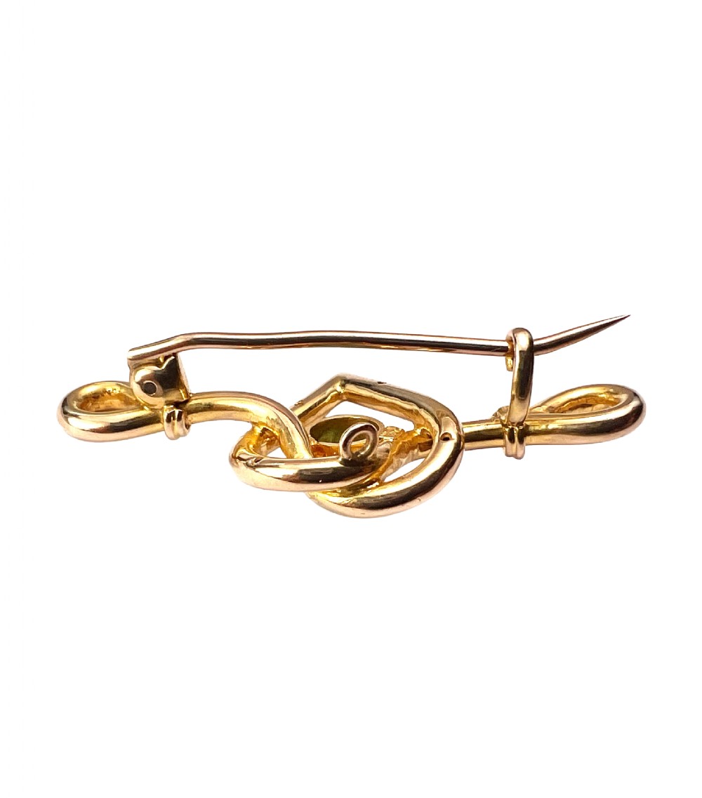 An antique 15ct yellow gold bar brooch featuring a central entwined heart motif set with a round turquoise cabochon stone. View V
