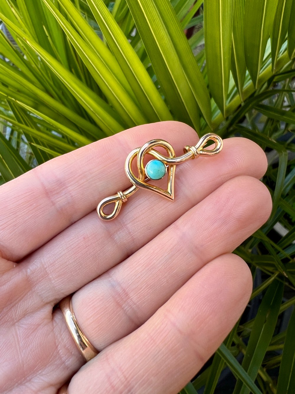 An antique 15ct yellow gold bar brooch featuring a central entwined heart motif set with a round turquoise cabochon stone. View IX