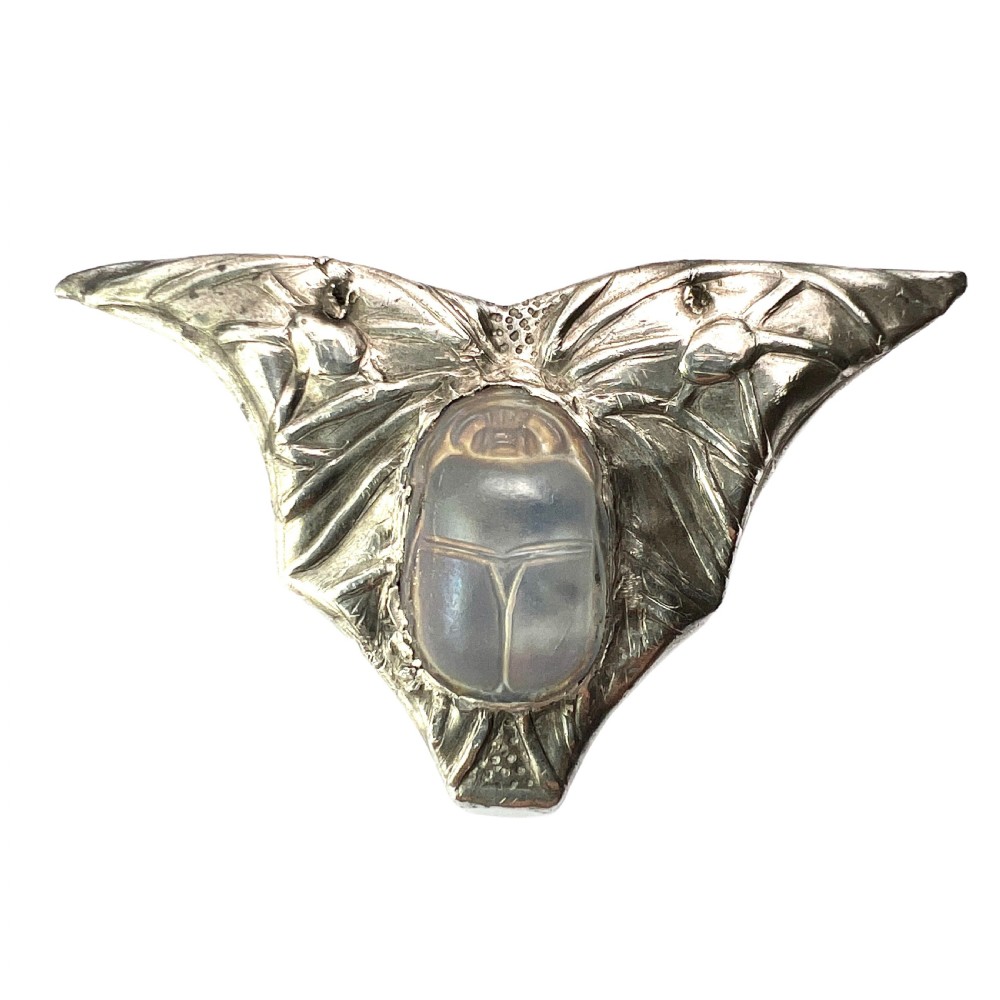 An antique pewter Art Nouveau brooch featuring a central translucent scarab beetle cabochon flanked by outstretched stylized wings.