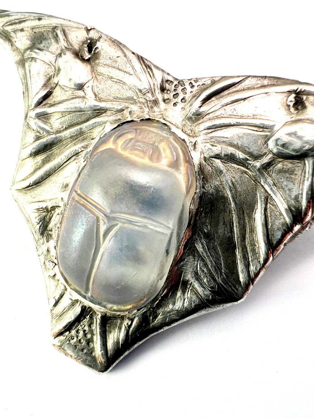 An antique pewter Art Nouveau brooch featuring a central translucent scarab beetle cabochon flanked by outstretched stylized wings. View III