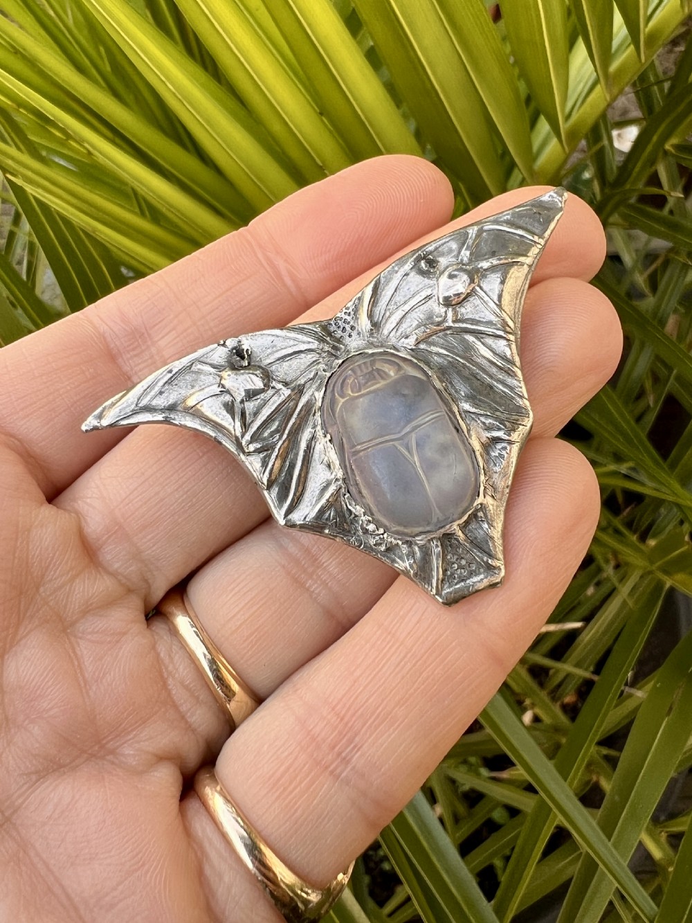 An antique pewter Art Nouveau brooch featuring a central translucent scarab beetle cabochon flanked by outstretched stylized wings. View VIII