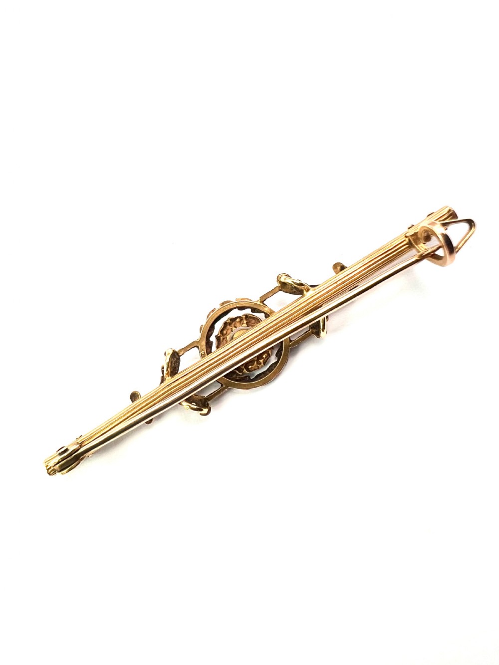 An antique 18-carat yellow gold bar brooch featuring a central circular motif with a round red garnet flanked by seed pearls and fluted bar details. View VI